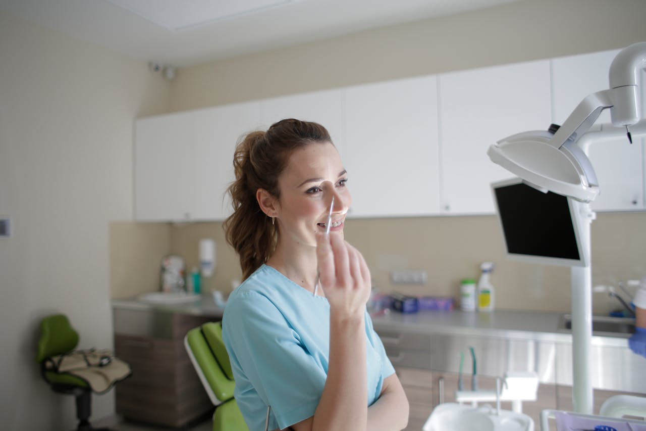 Cheerful female dental professional holding tools in a bright, modern clinic.